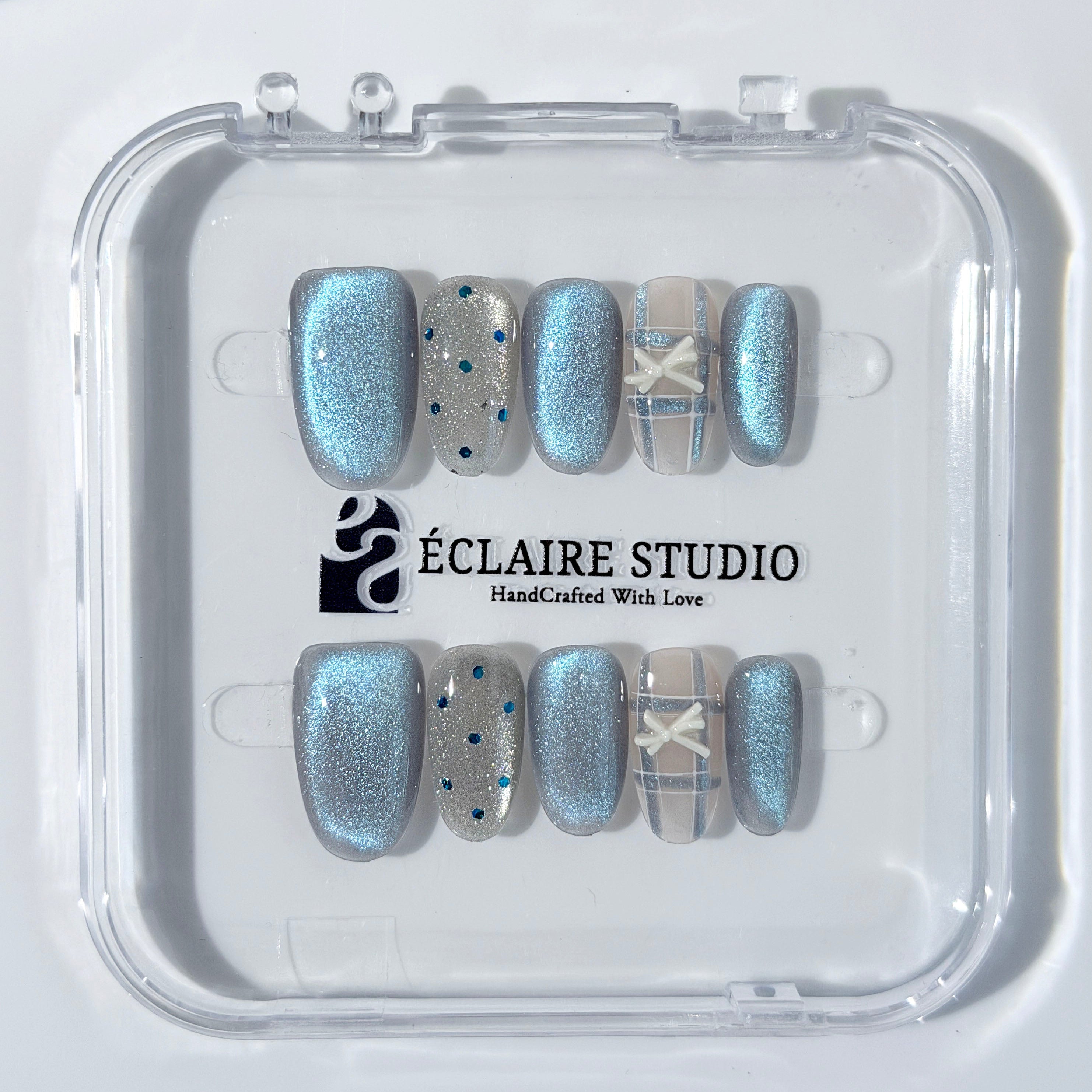 Pastel blue cat-eye press-on nails with glitter accents and 3D clear star details in a soft winter sorbet aesthetic.