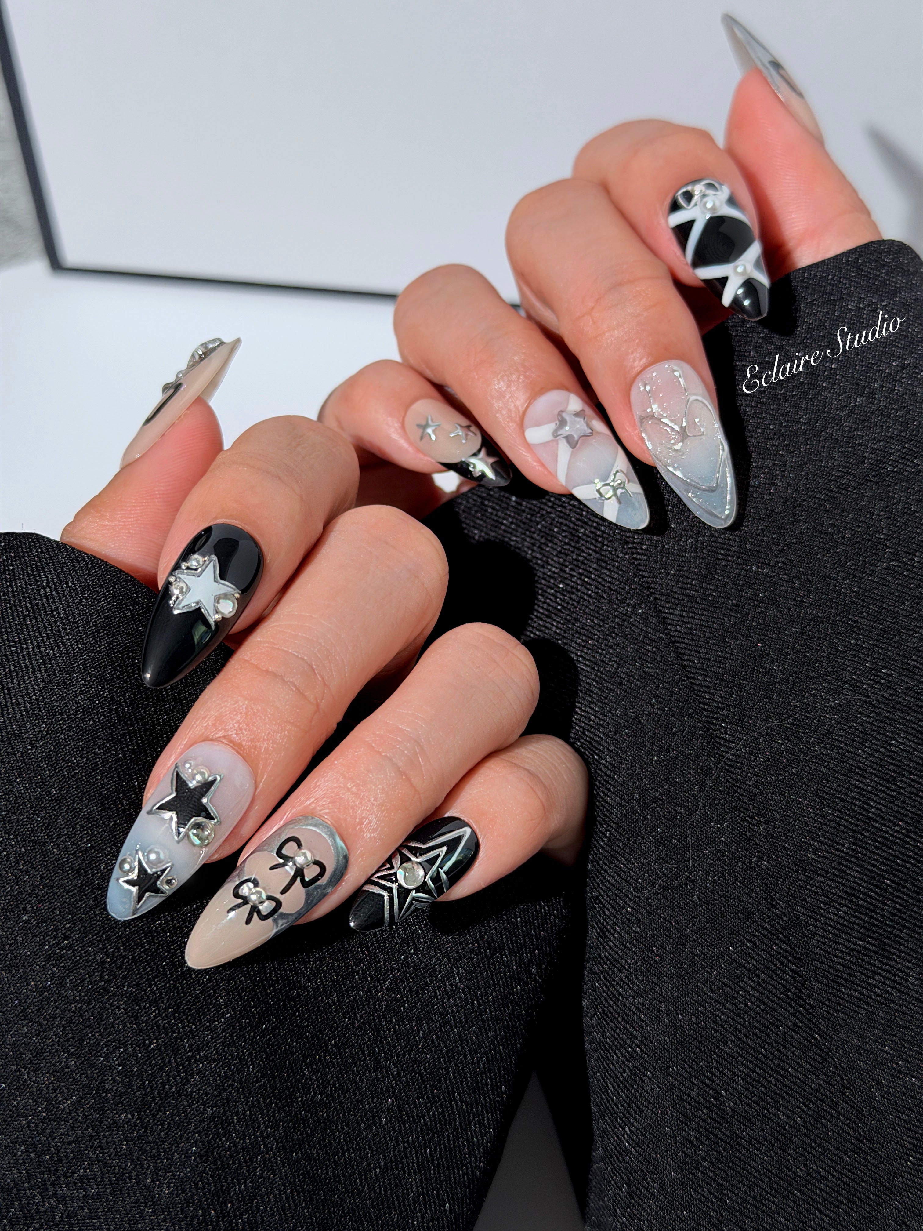 Handmade black, white, and nude press-on nails featuring bows, star charms, and pearl embellishments.