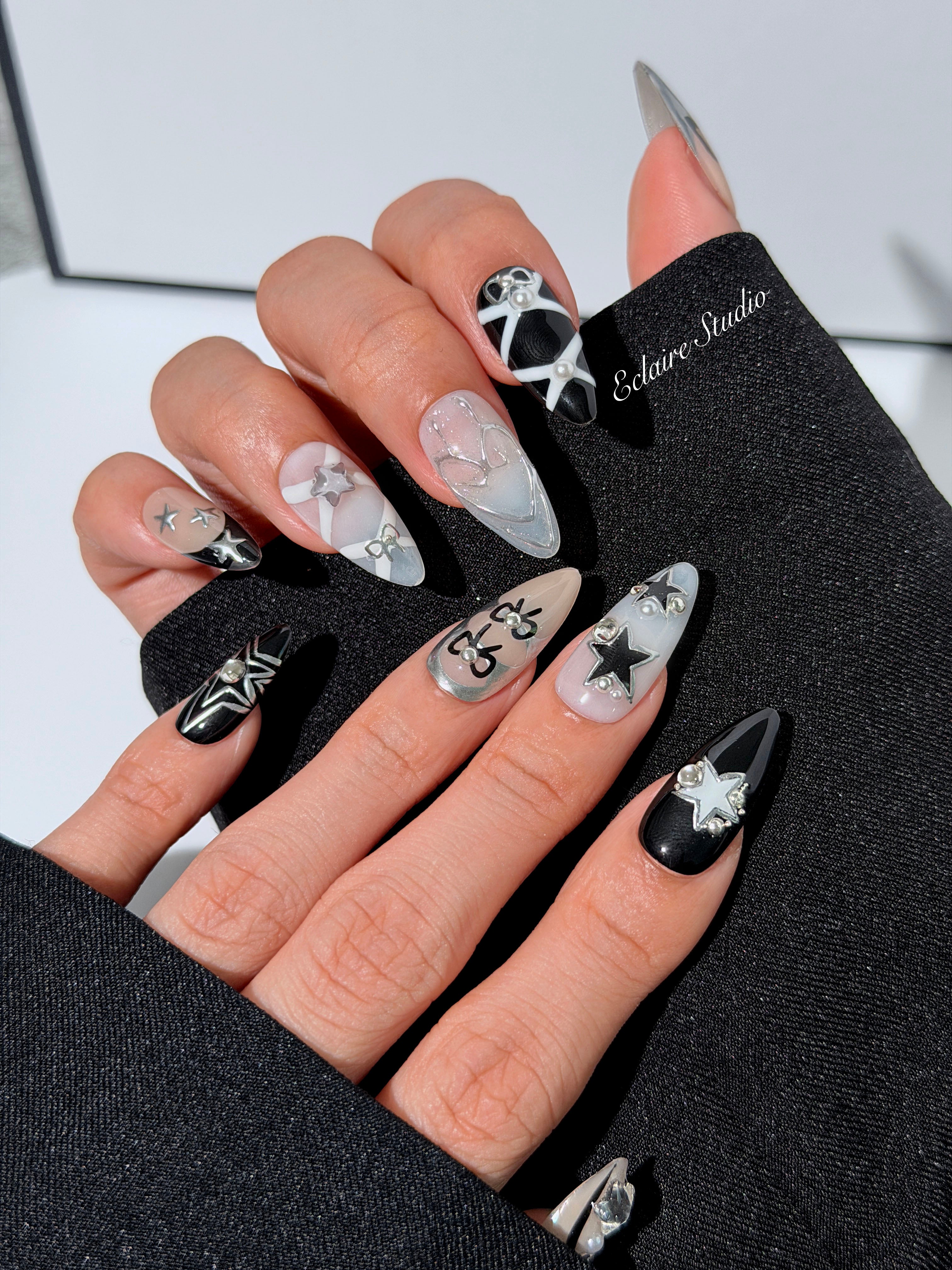 Handmade black, white, and nude press-on nails featuring bows, star charms, and pearl embellishments.