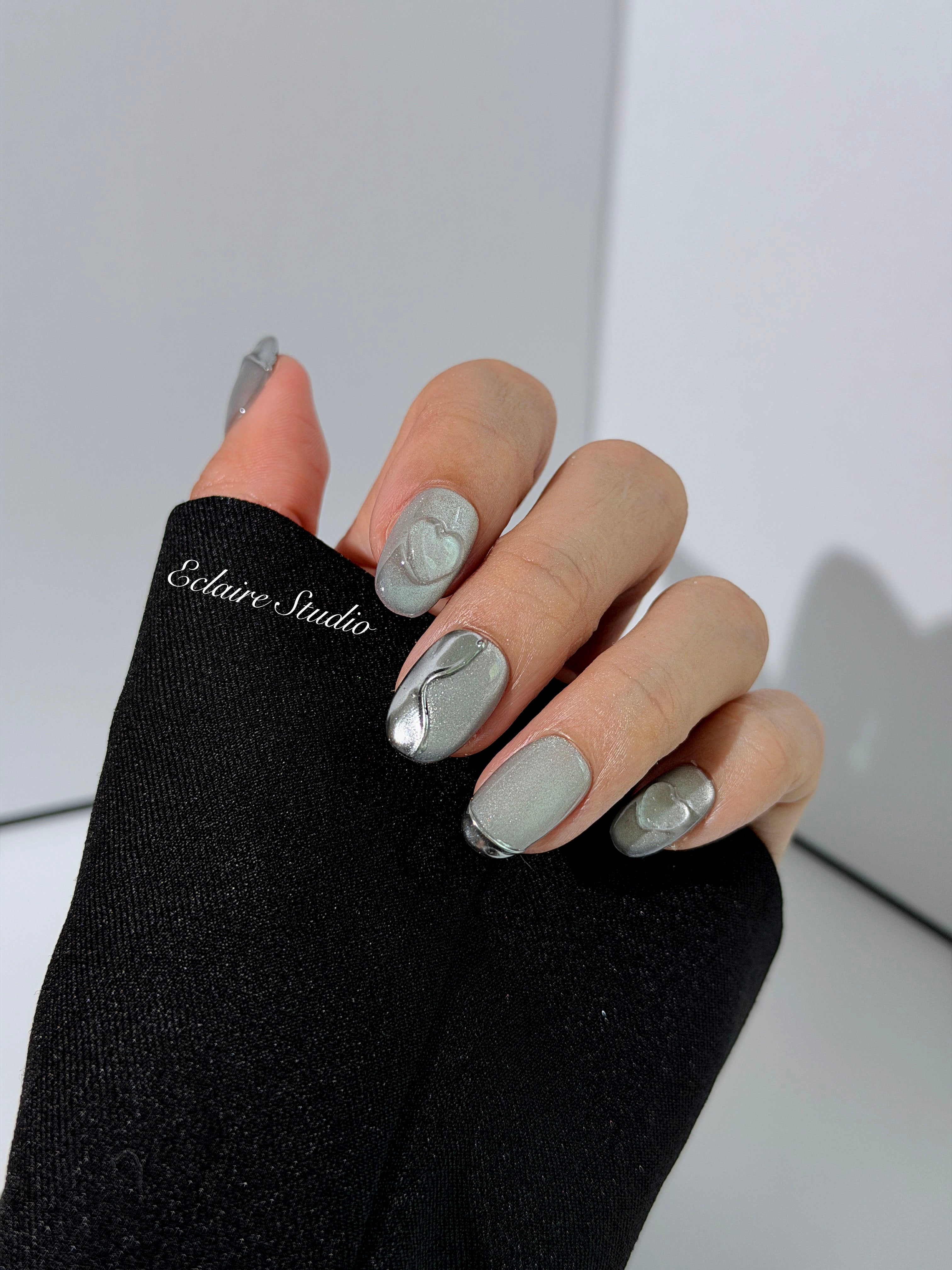 Extra short silver cat-eye press-on nails with chrome ripple accents and 3D heart details, minimalist winter aesthetic.