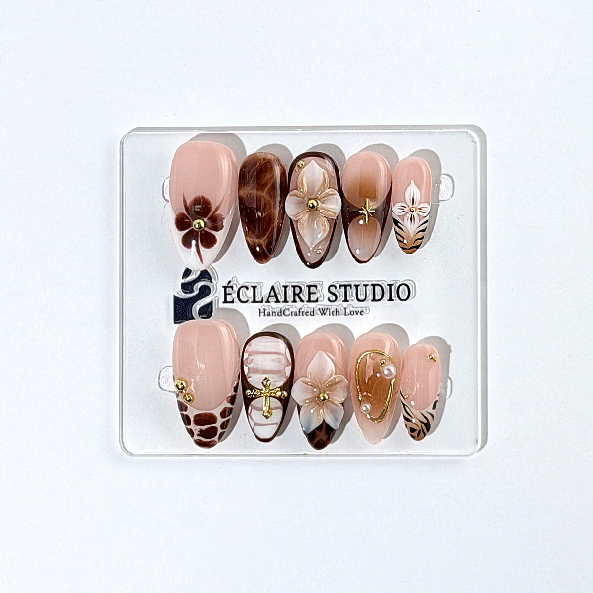 Petal Locket almond press-on nails with nude bases, ivory 3D flowers, brown florals, tortoiseshell, animal-print French tips, pearls, and gold accents.