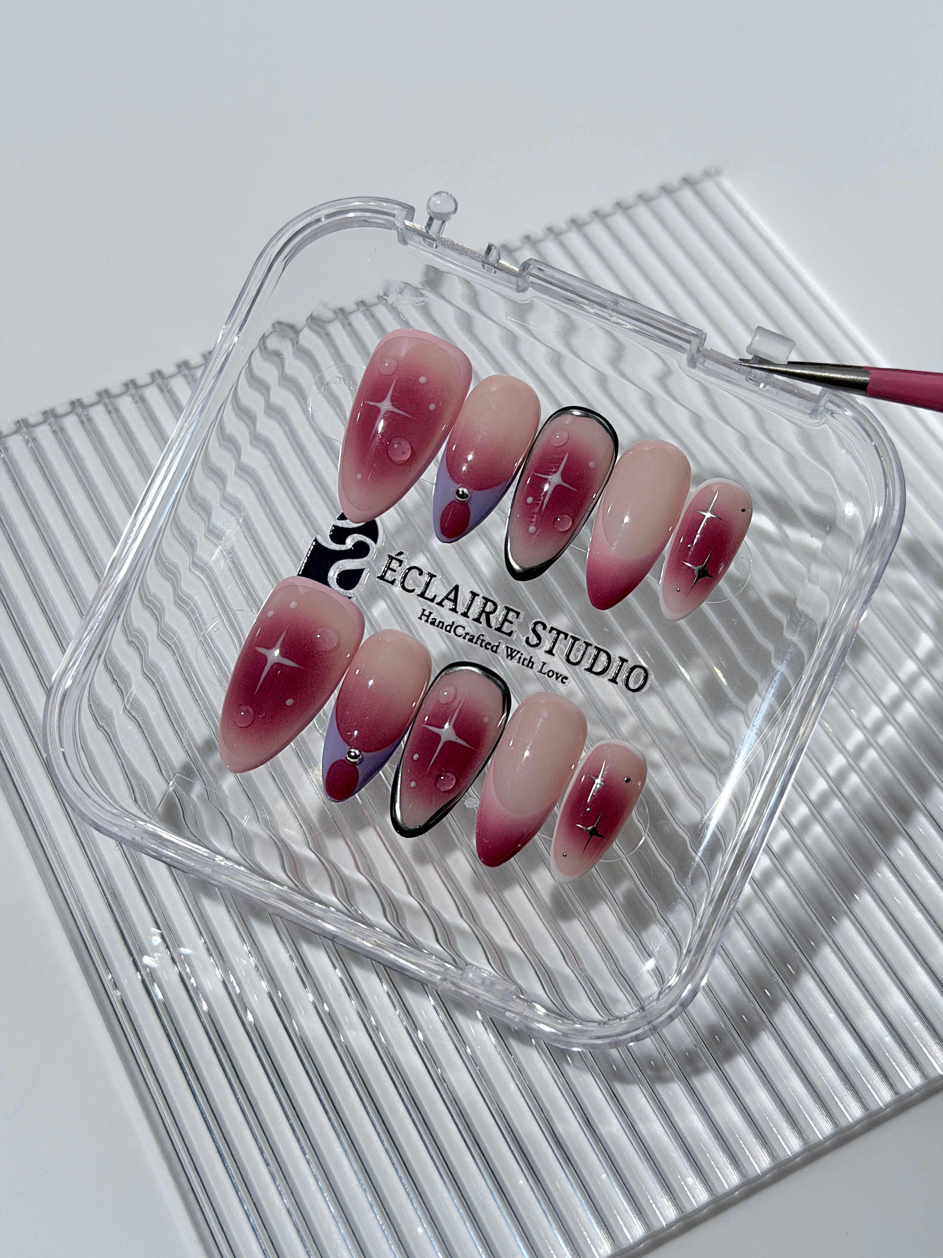 Plum and blush ombré nails with star accents and abstract black outlines — Sugar Plum Fairy–inspired.