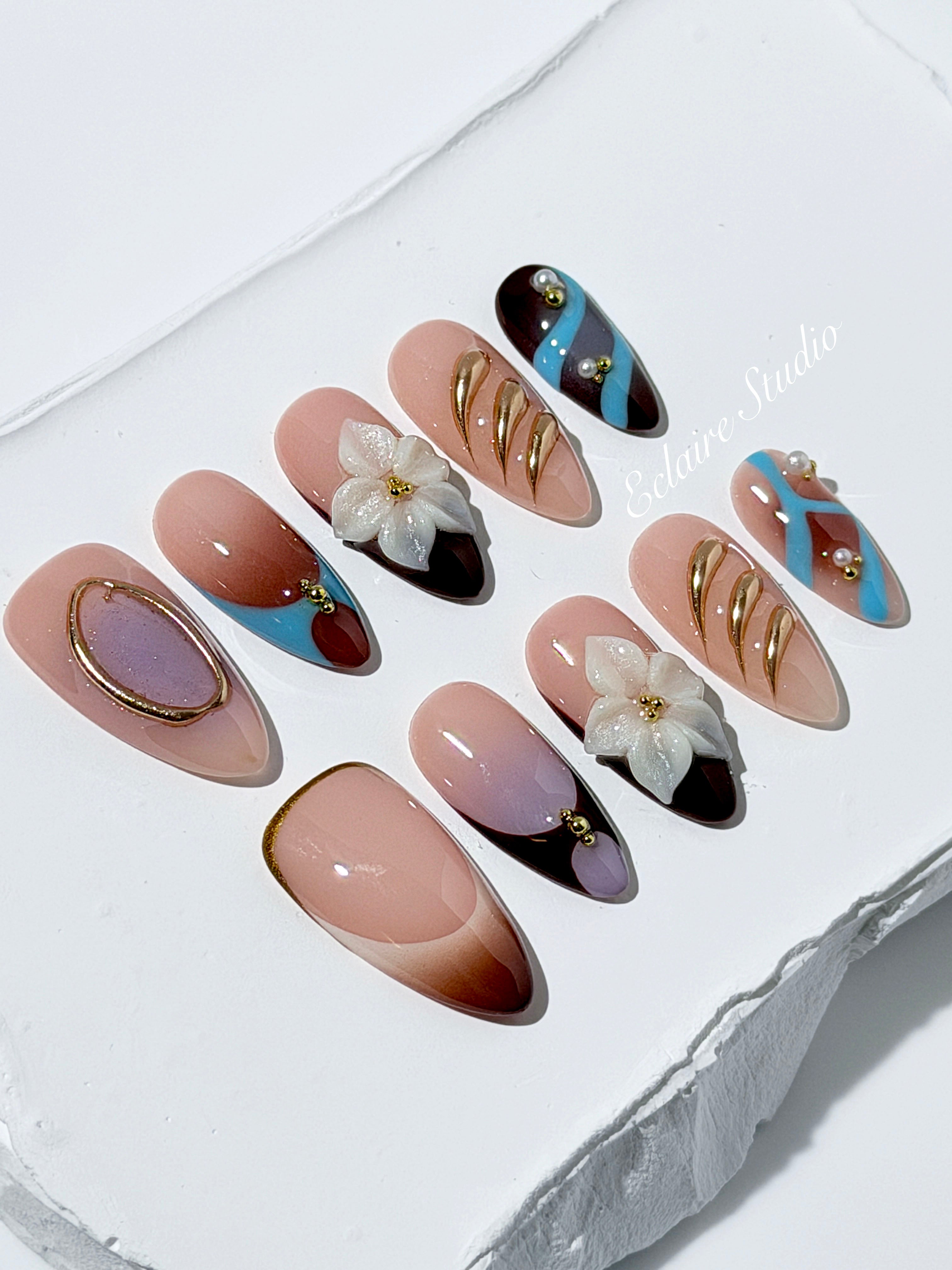 Warm gradient nails with gold trim, 3D white flowers, and blue accents inspired by the Nutcracker character