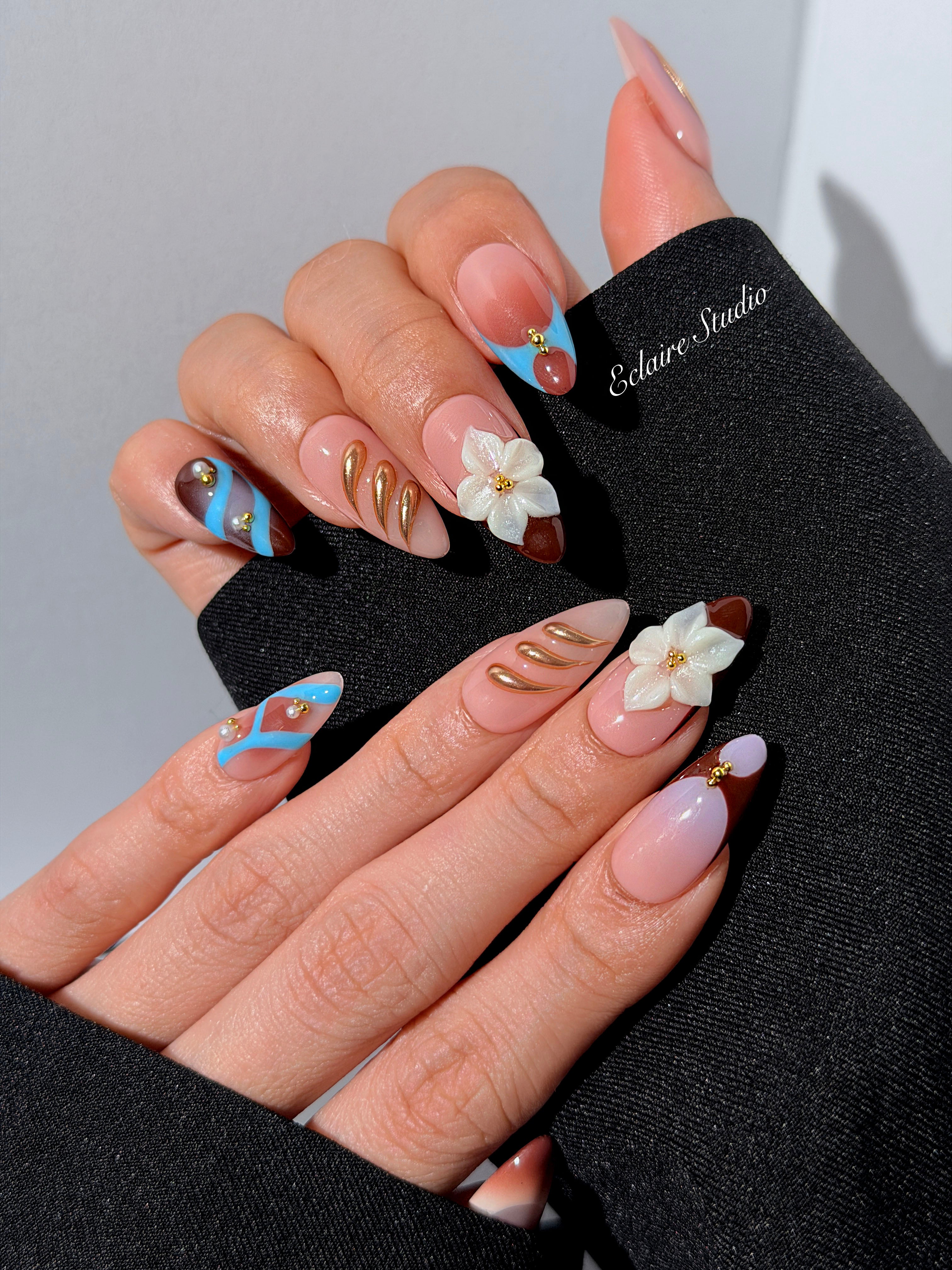 Warm gradient nails with gold trim, 3D white flowers, and blue accents inspired by the Nutcracker character