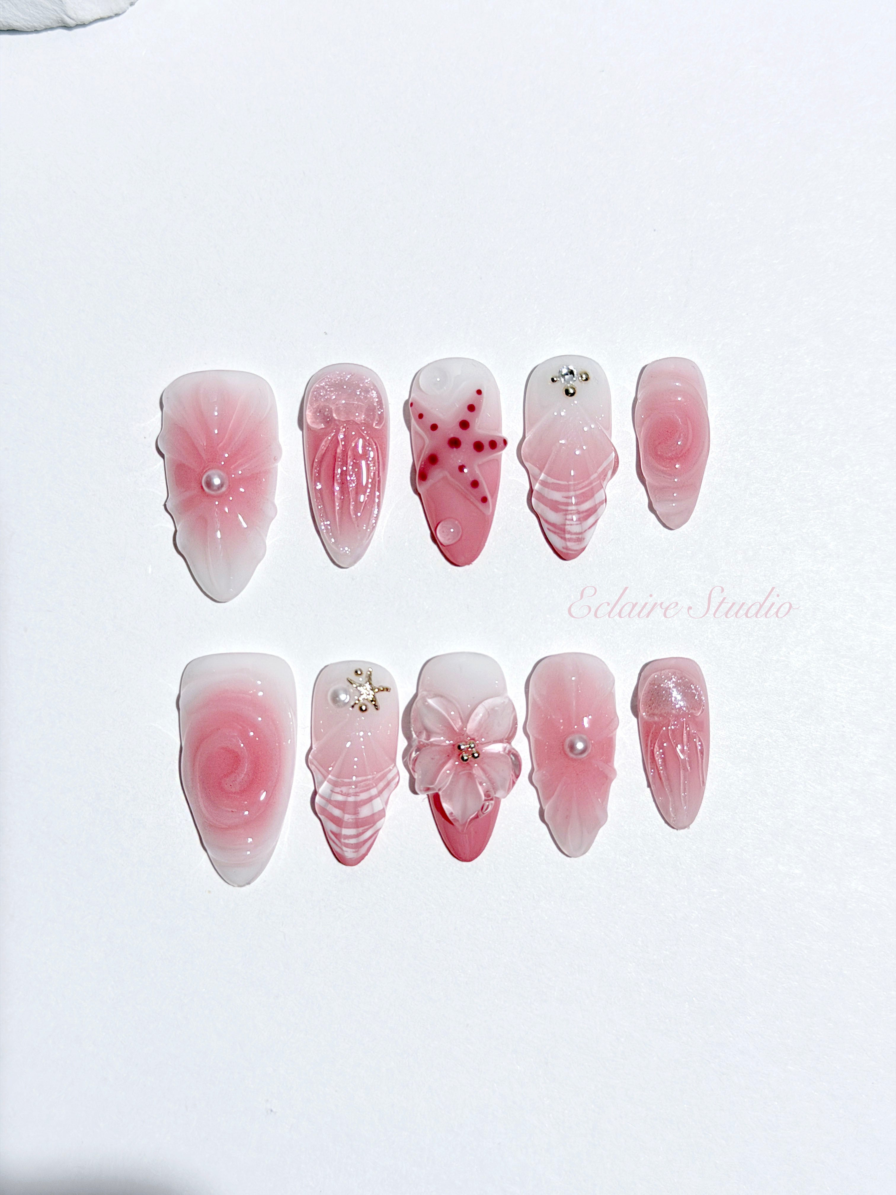 Luxury press-on nails featuring a soft blush pink ombre base with white French tips, a translucent 3D jellyfish, a sculpted pink starfish, and a clear 3D glass flower with a pearl center.