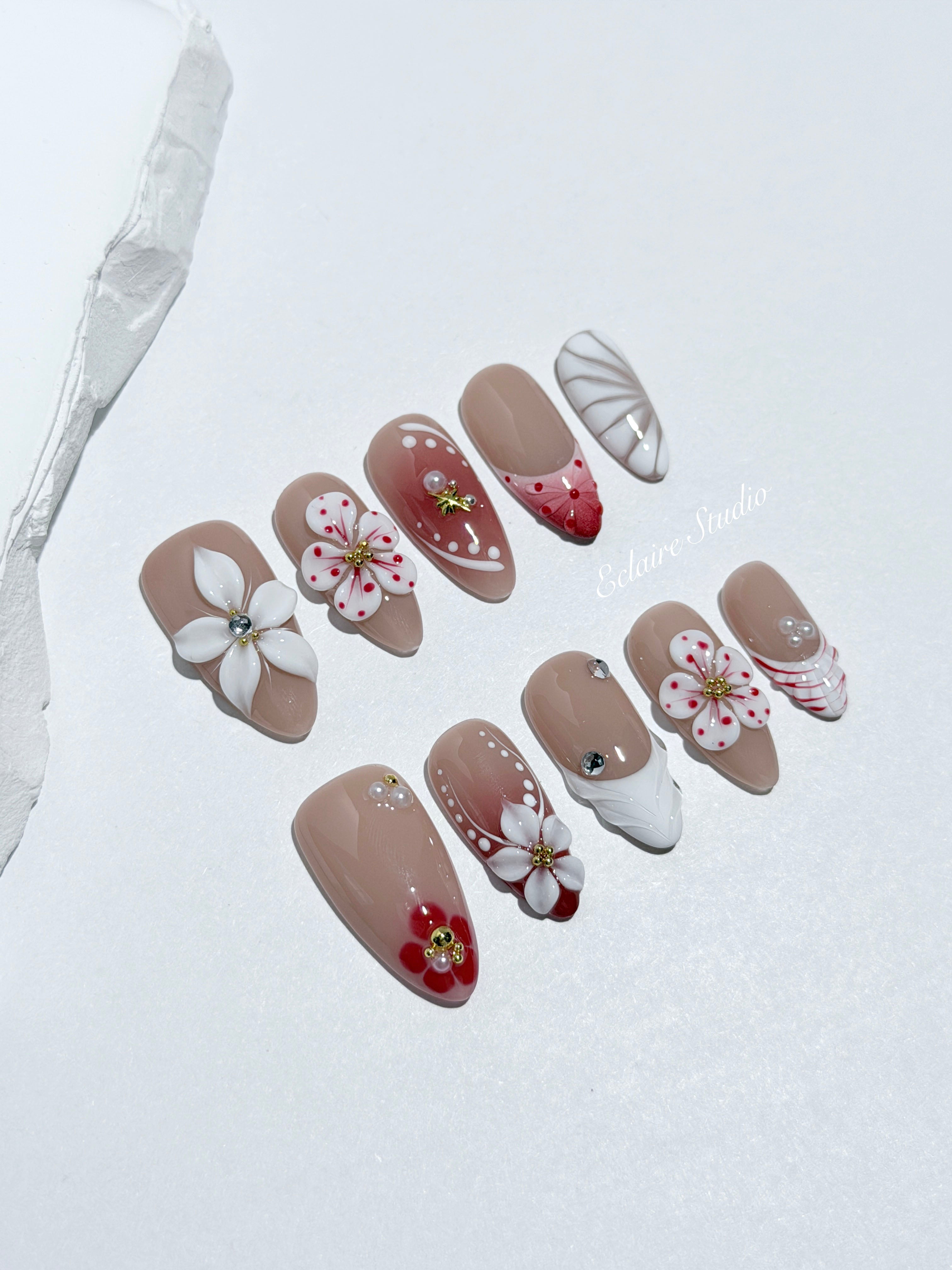 Rouge press-on nails with red linework and 3D white florals on a nude base – Éclaire Studio