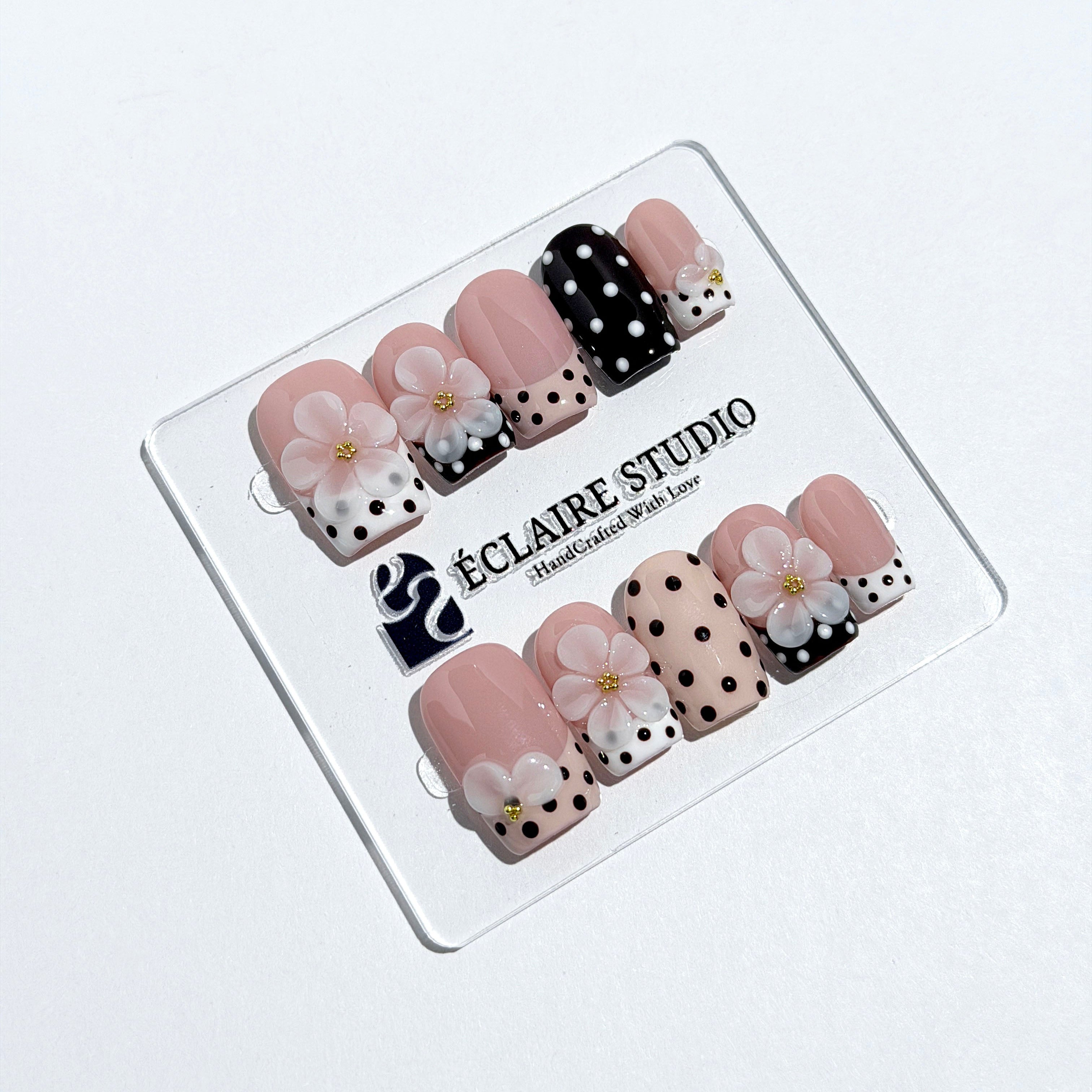 Eclaire Nail Studio 3D Floral Polka dot pink base with alternating black and white polka dot French tips, and hand-sculpted 3D frosted white flowers with gold bead centers, Medium Square
