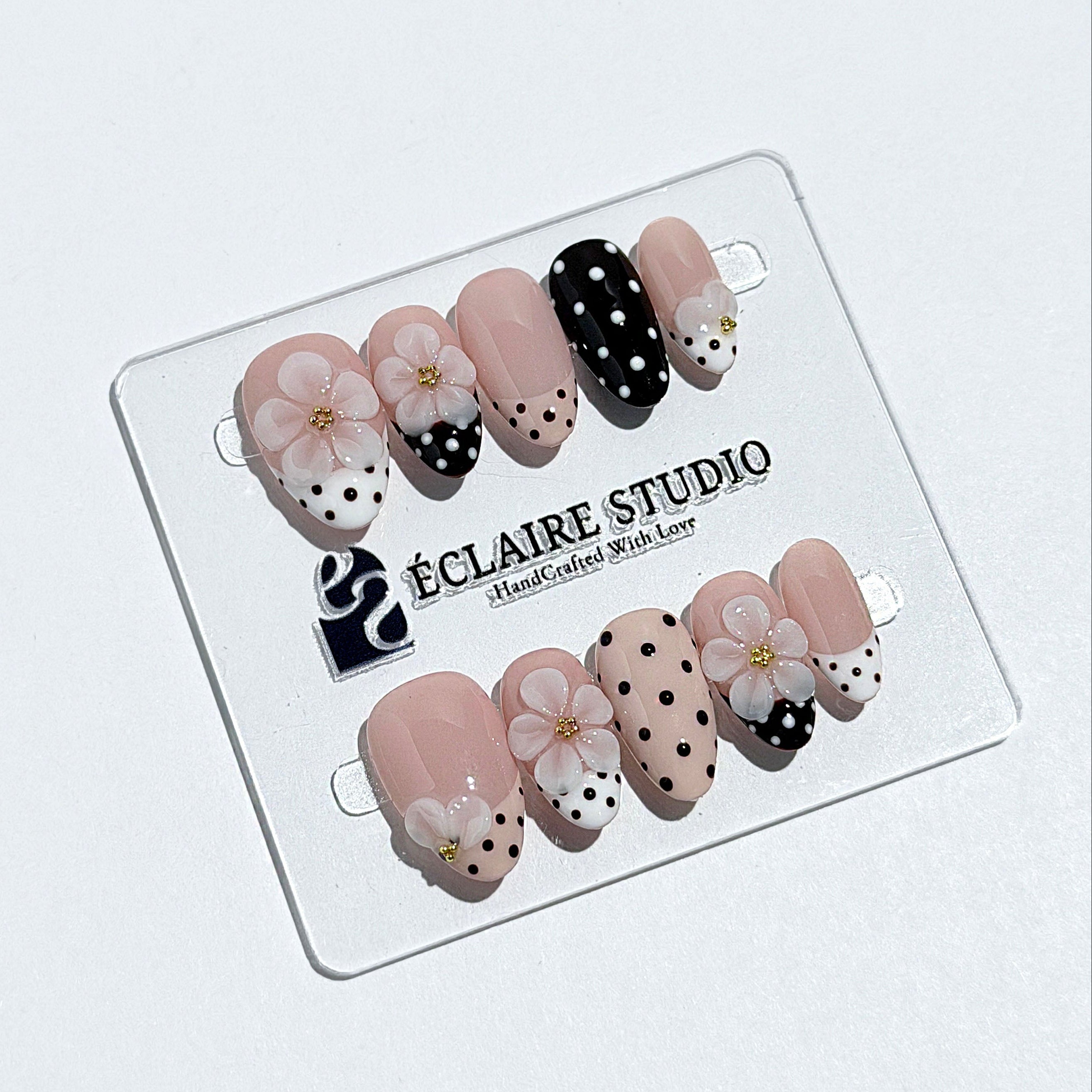 Eclaire Nail Studio 3D Floral Polka dot pink base with alternating black and white polka dot French tips, and hand-sculpted 3D frosted white flowers with gold bead centers, Short Almond