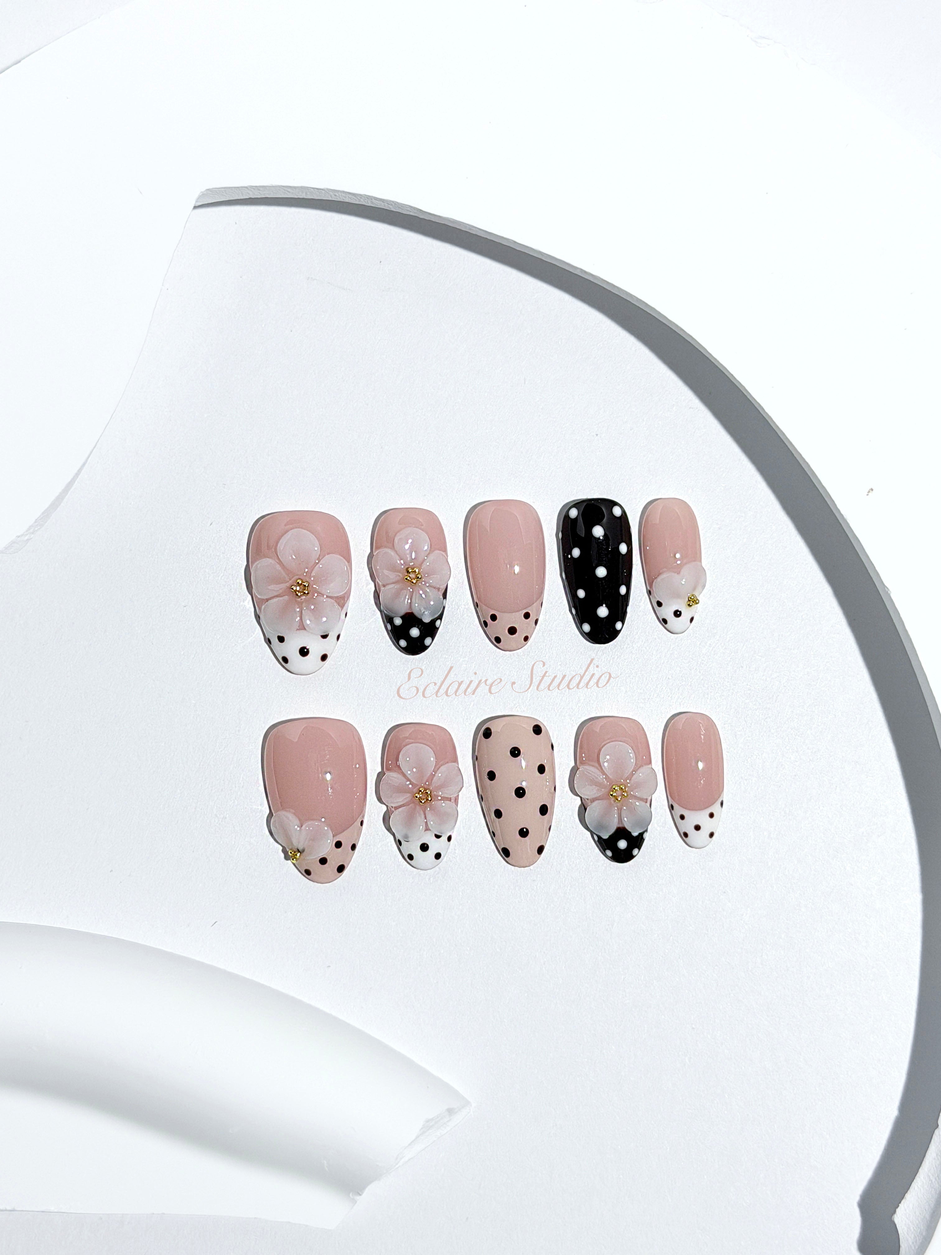 Eclaire Nail Studio 3D Floral Polka dot pink base with alternating black and white polka dot French tips, and hand-sculpted 3D frosted white flowers with gold bead centers, Short Almond