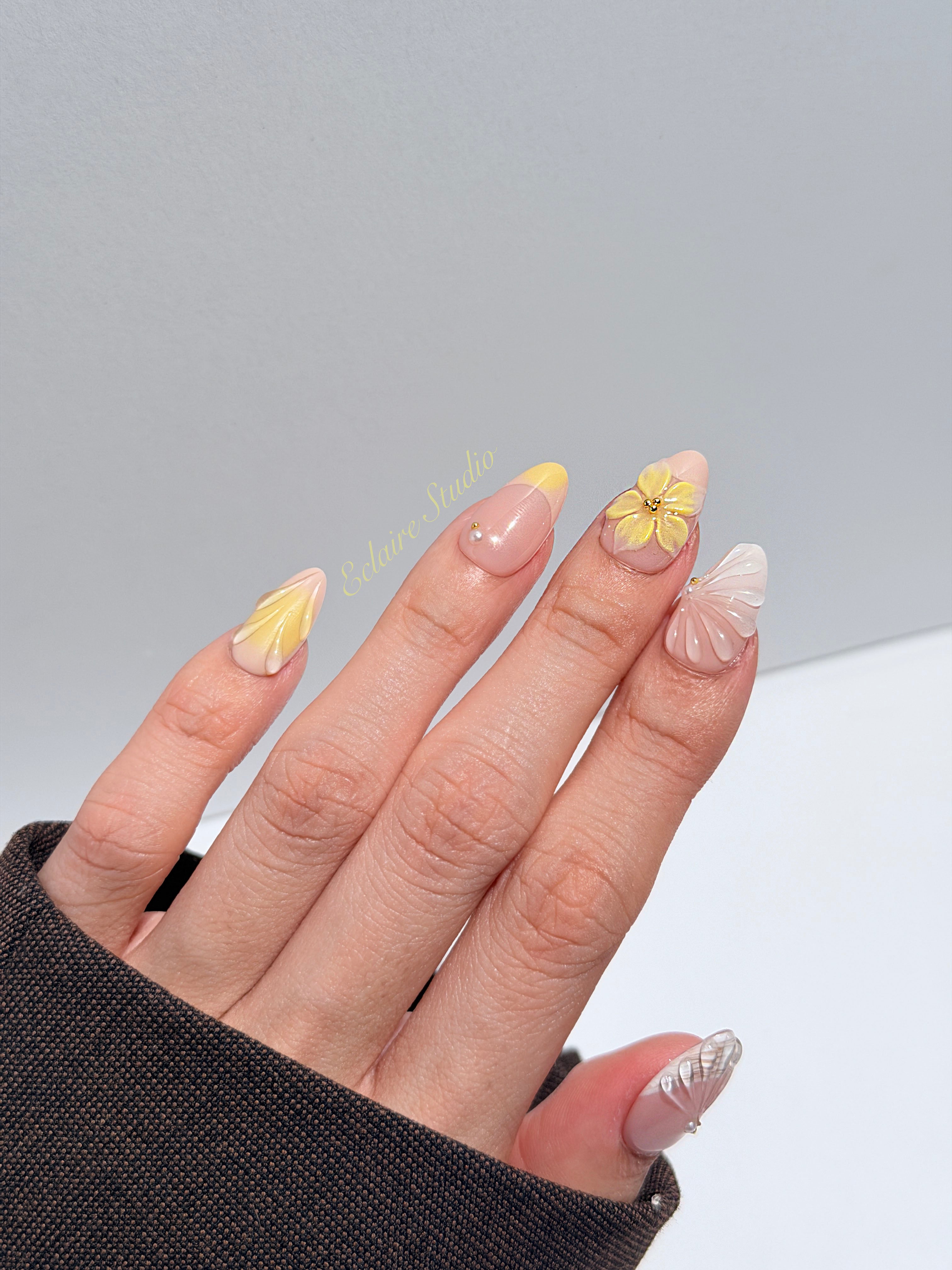 Eclaire Studio Yellow Summer short almond press-on nails featuring a sheer nude base with yellow French tips, hand-sculpted 3D flowers, frosted 3D seashells
