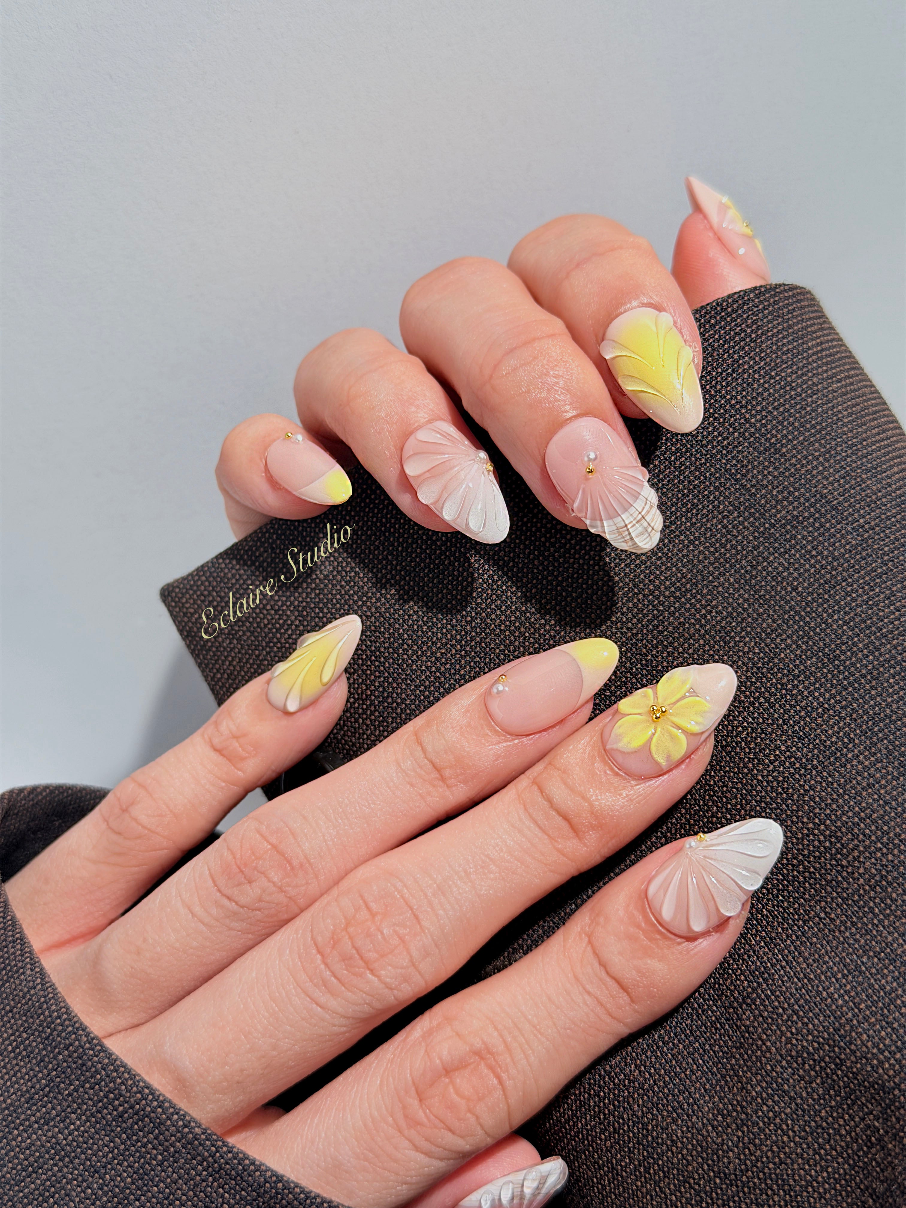 Eclaire Studio Yellow Summer short almond press-on nails featuring a sheer nude base with yellow French tips, hand-sculpted 3D flowers, frosted 3D seashells