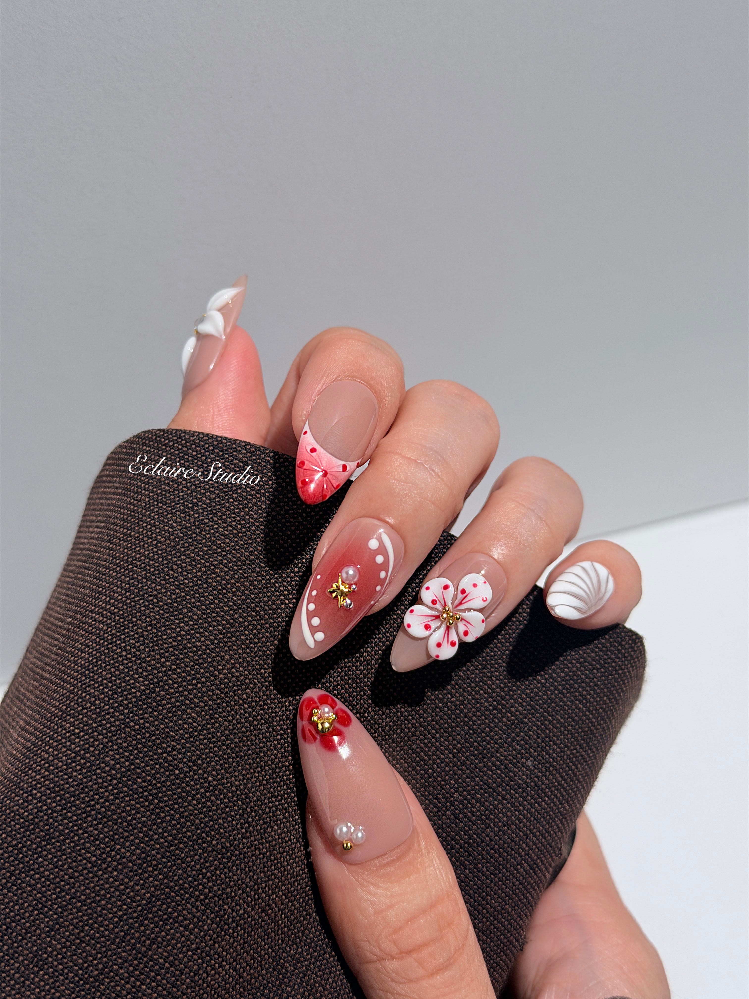 Rouge press-on nails with red linework and 3D white florals on a nude base – Éclaire Studio