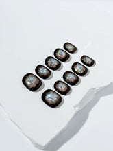 Short squoval press-on nails with dark brown base and iridescent frosted shimmer center, styled on white stone background.