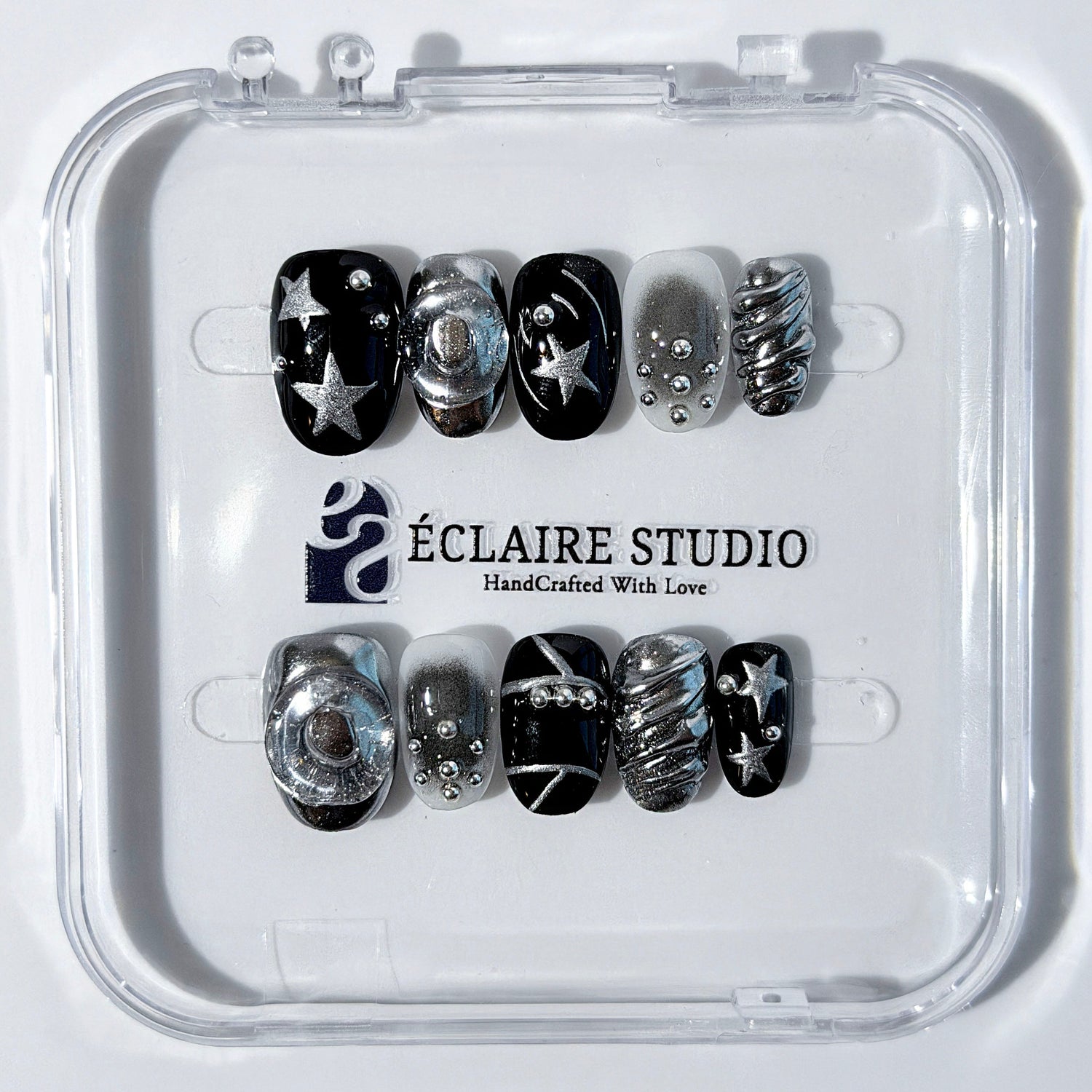 Black and silver press-on nails with 3D chrome swirl accents, star details, and shimmer gradient in a bold winter aesthetic.
Y2K nails