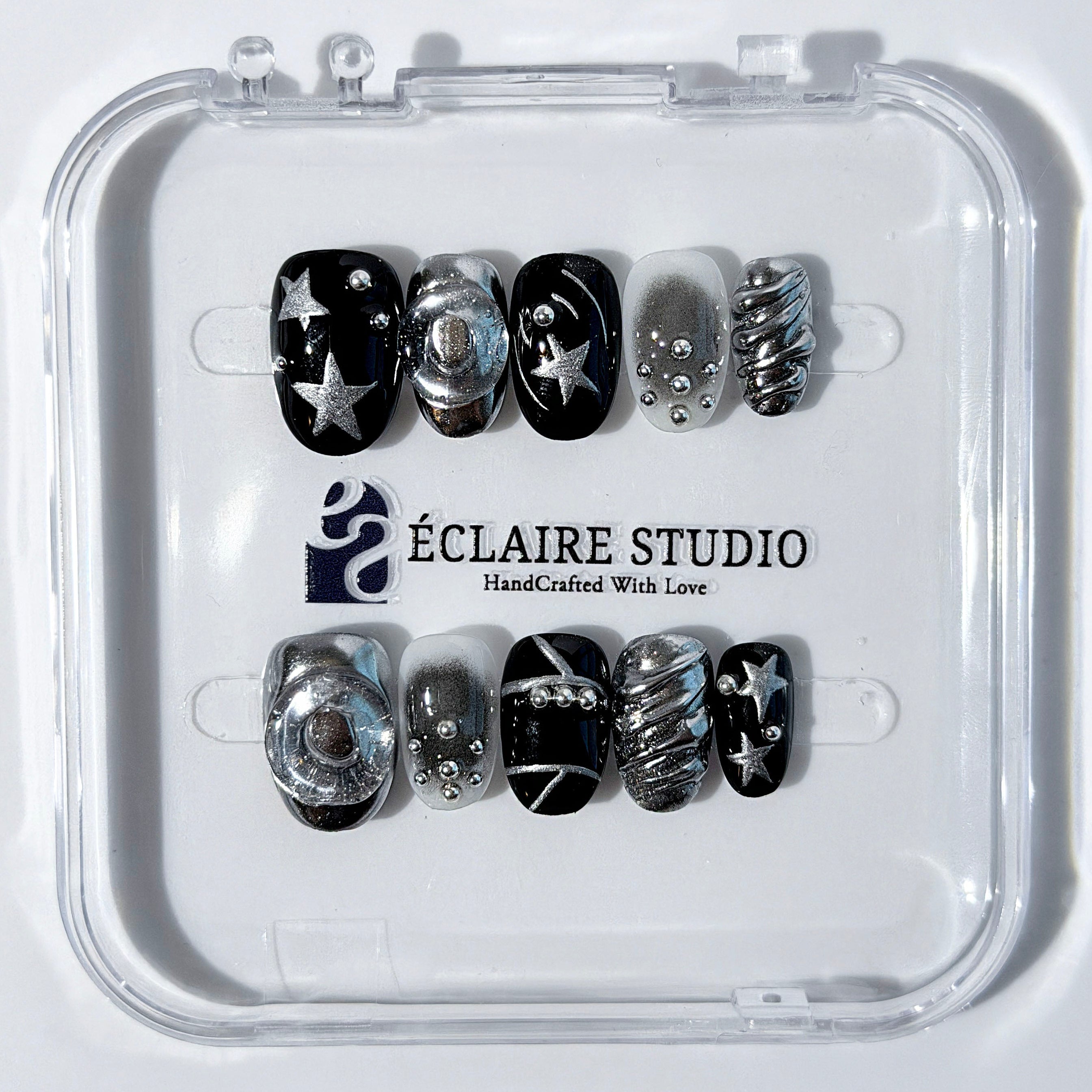 Black and silver press-on nails with 3D chrome swirl accents, star details, and shimmer gradient in a bold winter aesthetic.
Y2K nails