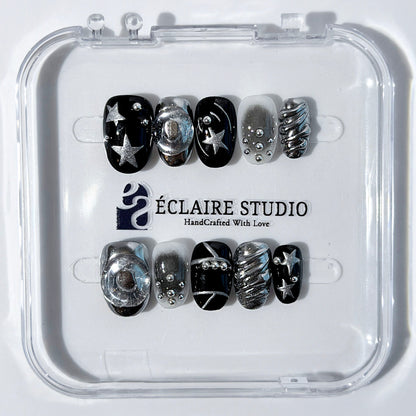 Black and silver press-on nails with 3D chrome swirl accents, star details, and shimmer gradient in a bold winter aesthetic.
Y2K nails