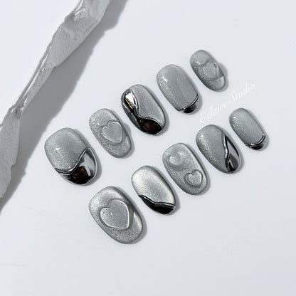 Extra short silver cat-eye press-on nails with chrome ripple accents and 3D heart details, minimalist winter aesthetic.
