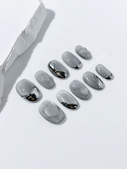 Extra short silver cat-eye press-on nails with chrome ripple accents and 3D heart details, minimalist winter aesthetic.

