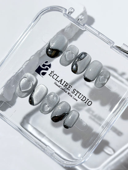Extra short silver cat-eye press-on nails with chrome ripple accents and 3D heart details, minimalist winter aesthetic.
