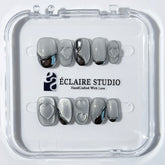 Extra short silver cat-eye press-on nails with chrome ripple accents and 3D heart details, minimalist winter aesthetic.

