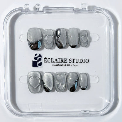 Extra short silver cat-eye press-on nails with chrome ripple accents and 3D heart details, minimalist winter aesthetic.

