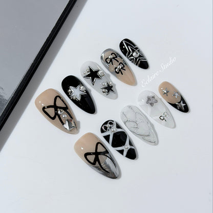 Handmade black, white, and nude press-on nails featuring bows, star charms, and pearl embellishments.