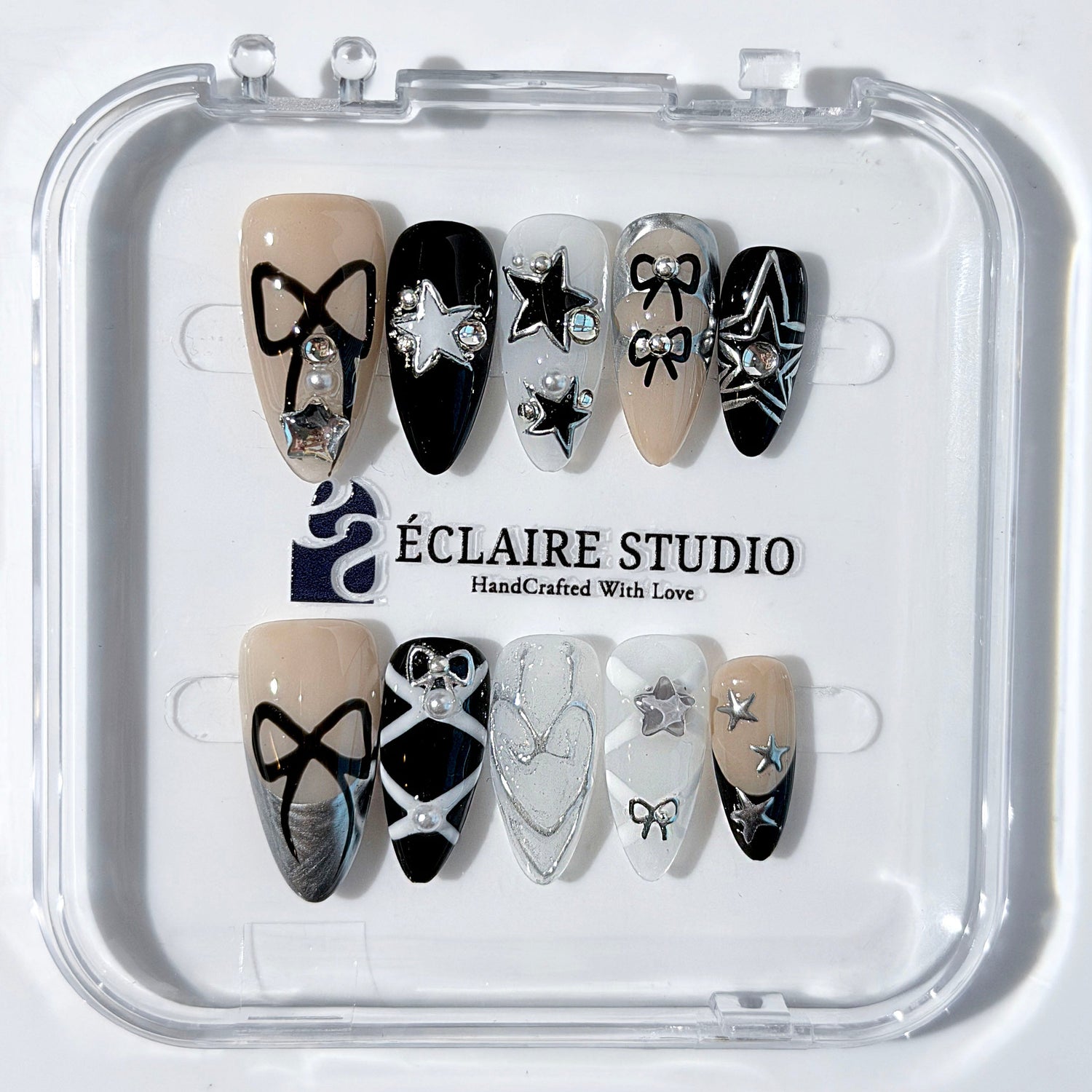 Handmade black, white, and nude press-on nails featuring bows, star charms, and pearl embellishments.
