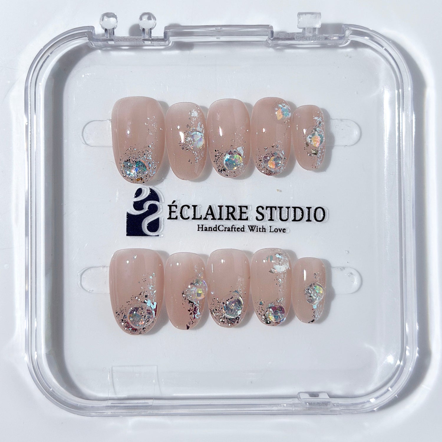 Short milky nude press-on nails with iridescent glitter and 3D crystal droplets, soft winter sugar aesthetic.
