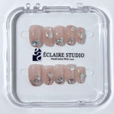 Short milky nude press-on nails with iridescent glitter and 3D crystal droplets, soft winter sugar aesthetic.
