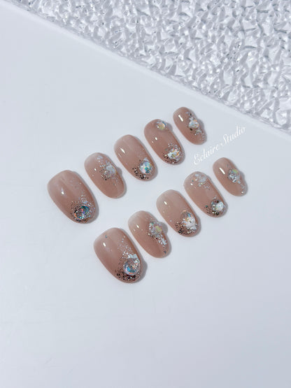 Short milky nude press-on nails with iridescent glitter and 3D crystal droplets, soft winter sugar aesthetic.
