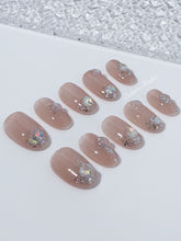Short milky nude press-on nails with iridescent glitter and 3D crystal droplets, soft winter sugar aesthetic.
