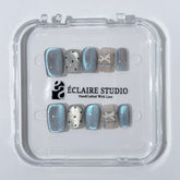 Pastel blue cat-eye press-on nails with glitter accents and 3D clear star details in a soft winter sorbet aesthetic.
