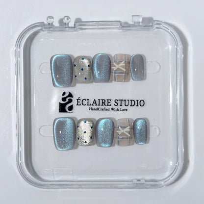Pastel blue cat-eye press-on nails with glitter accents and 3D clear star details in a soft winter sorbet aesthetic.
