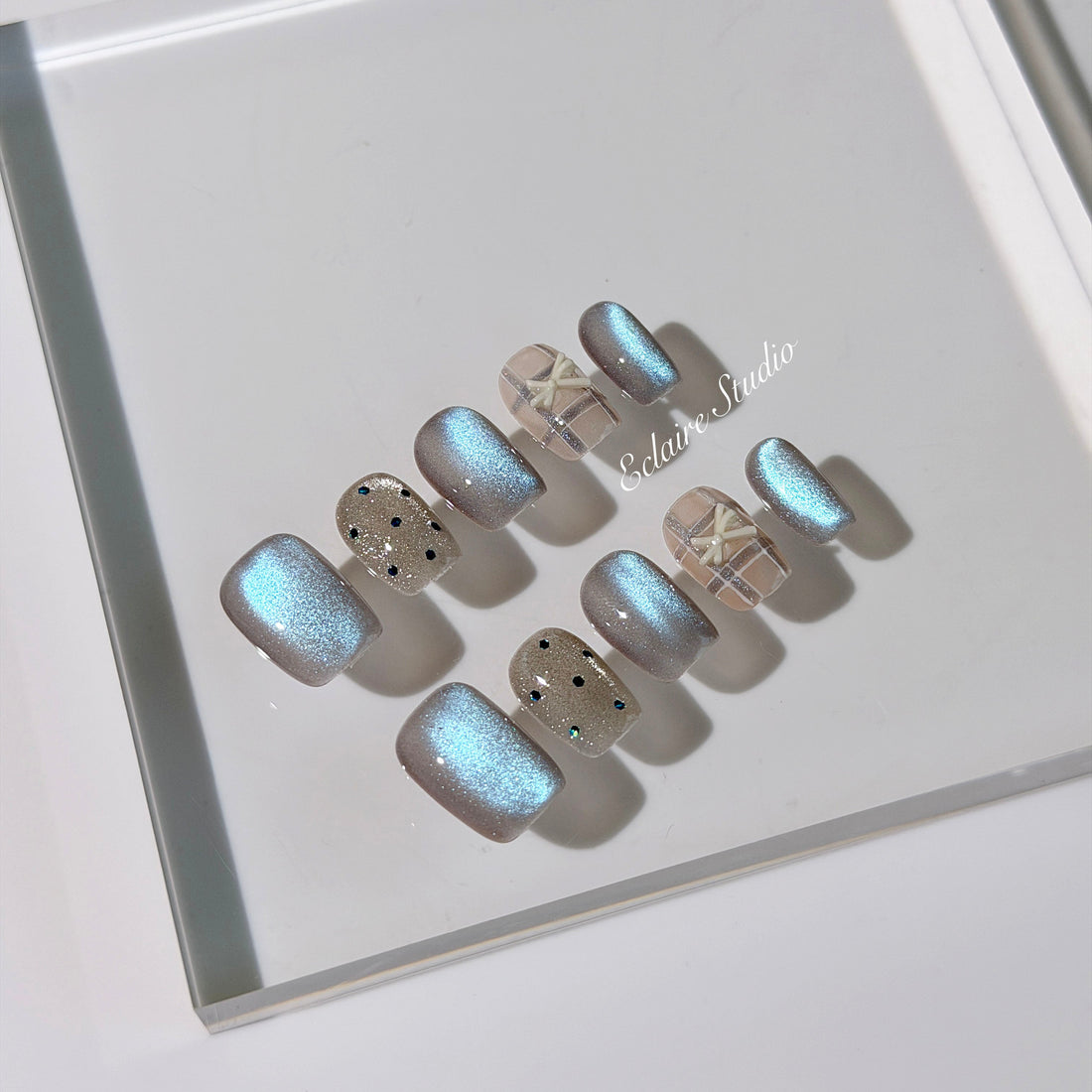 Pastel blue cat-eye press-on nails with glitter accents and 3D clear star details in a soft winter sorbet aesthetic.
