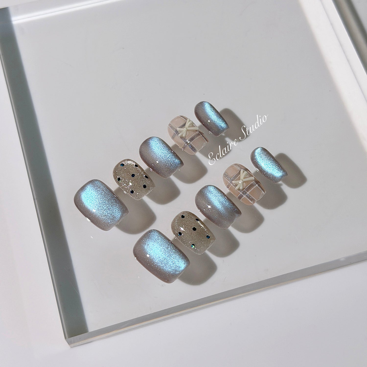 Pastel blue cat-eye press-on nails with glitter accents and 3D clear star details in a soft winter sorbet aesthetic.
