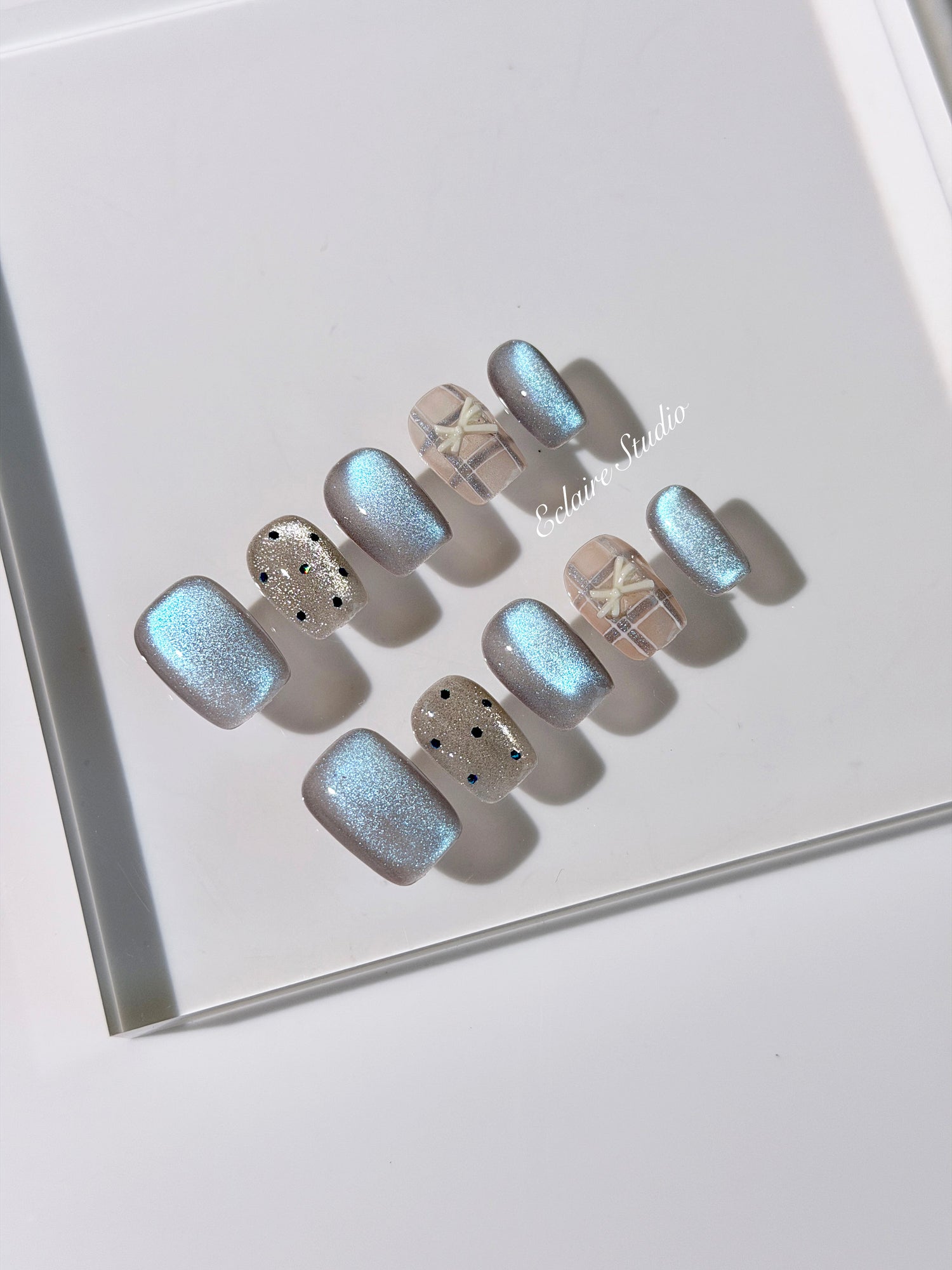 Pastel blue cat-eye press-on nails with glitter accents and 3D clear star details in a soft winter sorbet aesthetic.
