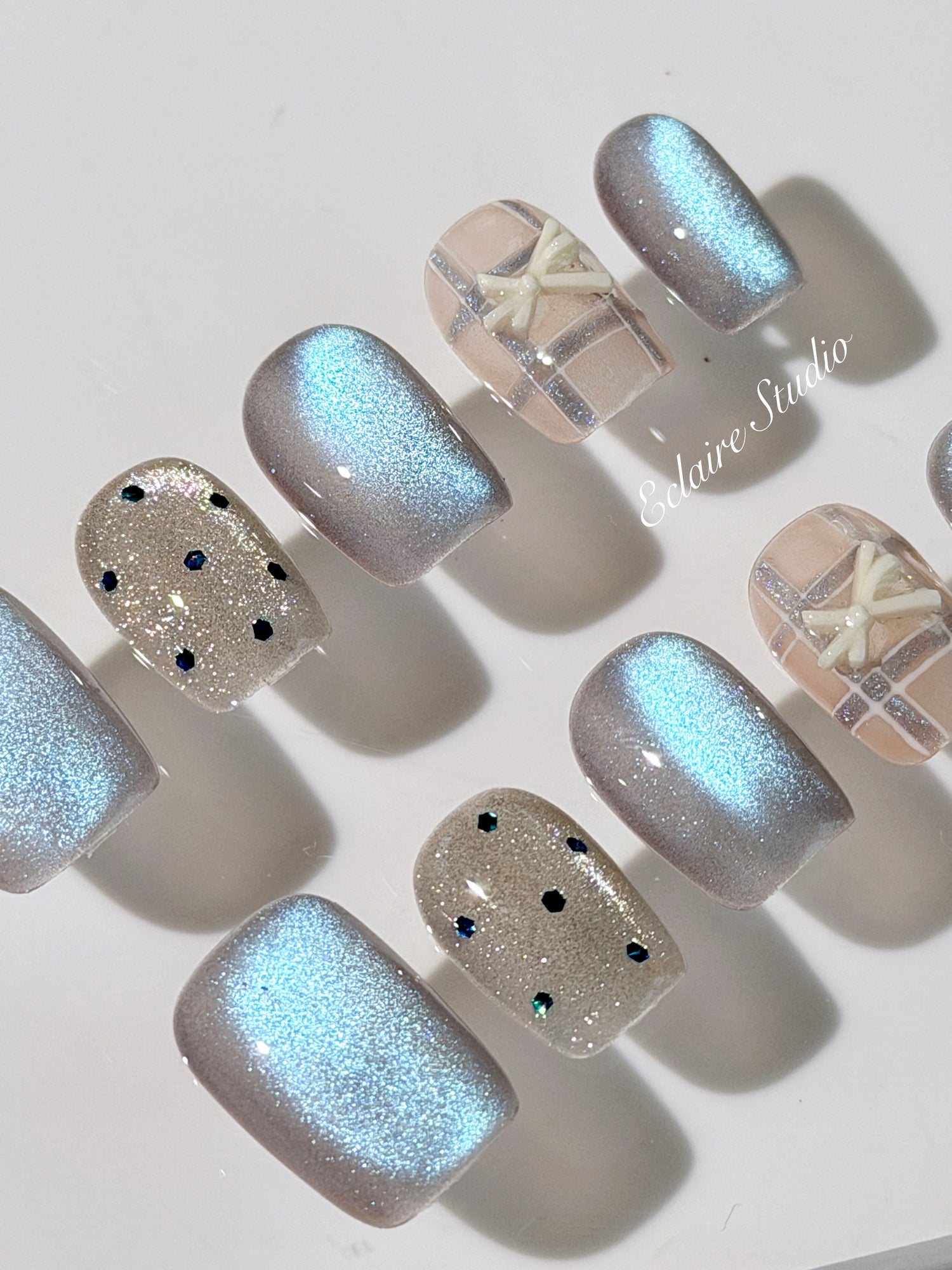 Pastel blue cat-eye press-on nails with glitter accents and 3D clear star details in a soft winter sorbet aesthetic.
