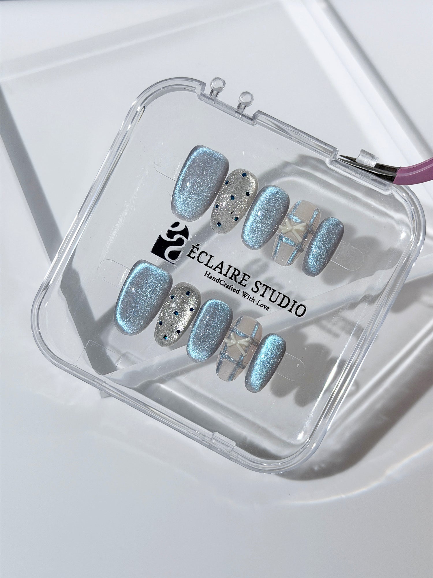 Pastel blue cat-eye press-on nails with glitter accents and 3D clear star details in a soft winter sorbet aesthetic.
