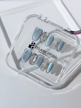 Pastel blue cat-eye press-on nails with glitter accents and 3D clear star details in a soft winter sorbet aesthetic.
