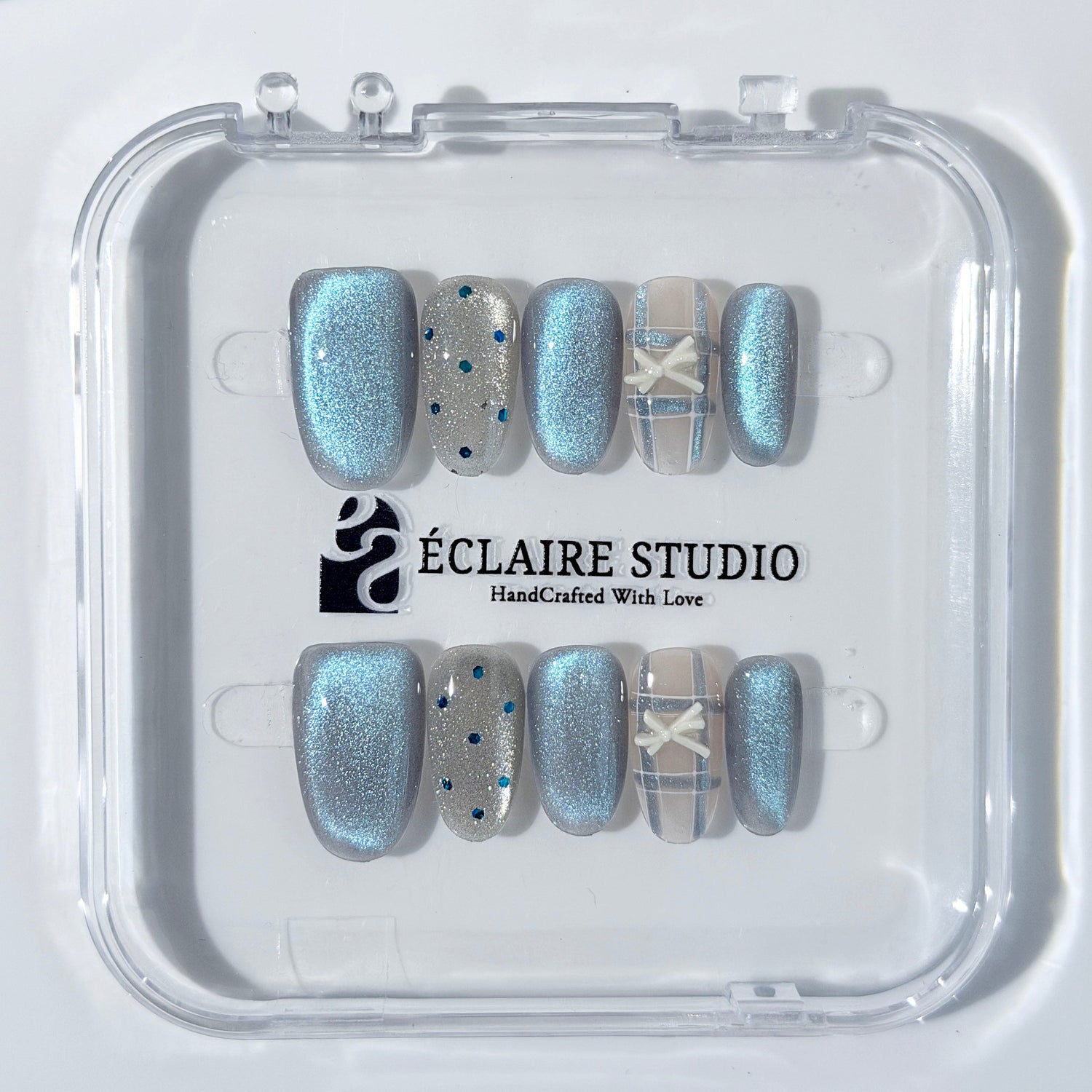 Pastel blue cat-eye press-on nails with glitter accents and 3D clear star details in a soft winter sorbet aesthetic.
