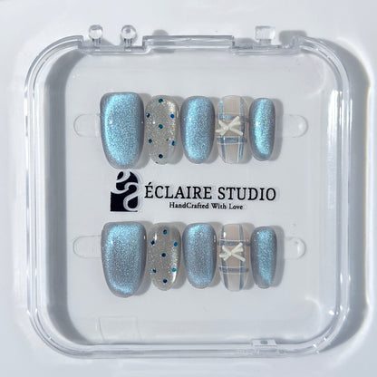 Pastel blue cat-eye press-on nails with glitter accents and 3D clear star details in a soft winter sorbet aesthetic.
