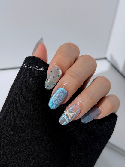 Pastel blue cat-eye press-on nails with glitter accents and 3D clear star details in a soft winter sorbet aesthetic.
