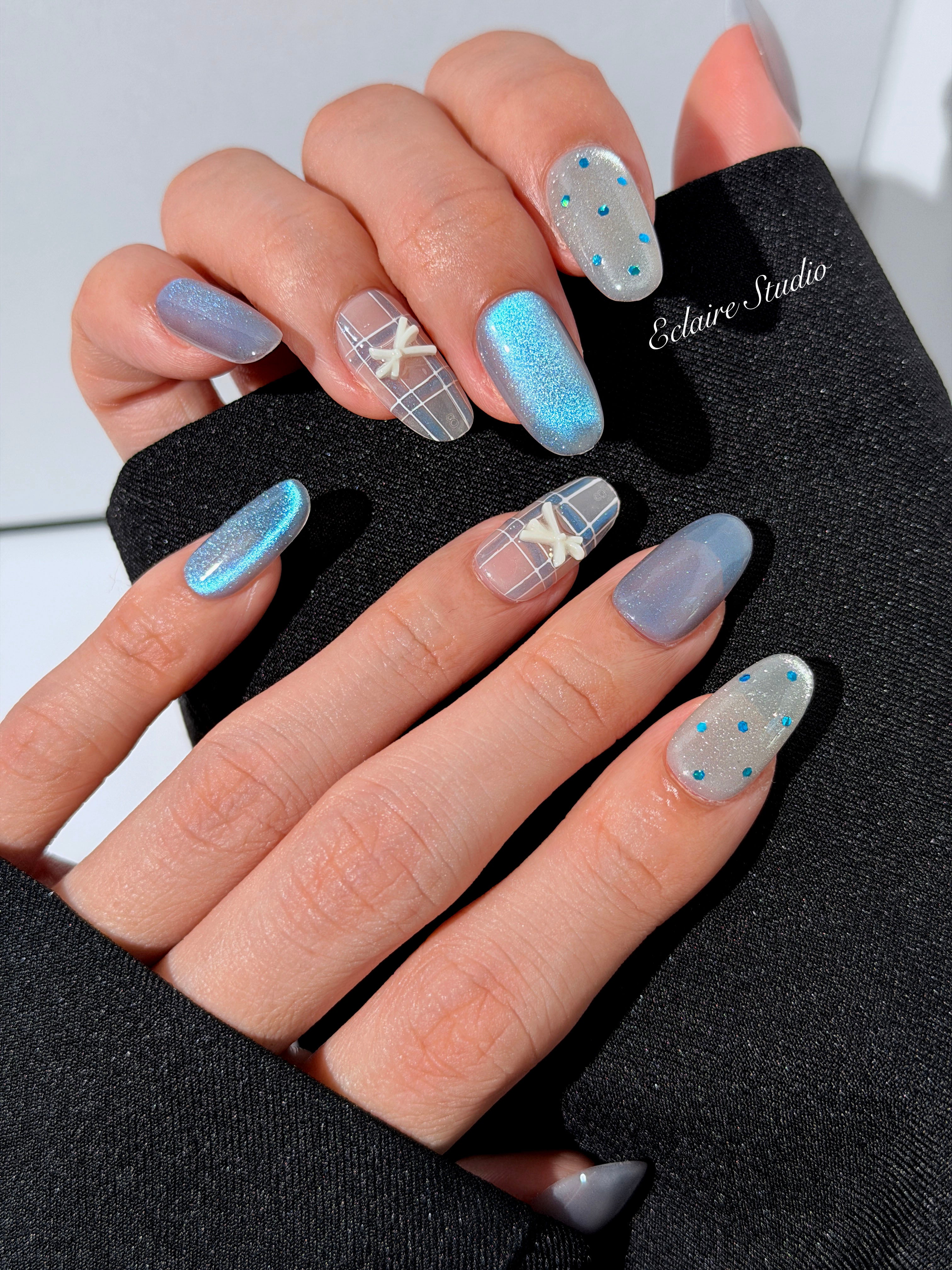 Pastel blue cat-eye press-on nails with glitter accents and 3D clear star details in a soft winter sorbet aesthetic.
