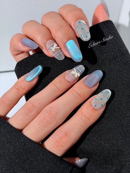 Pastel blue cat-eye press-on nails with glitter accents and 3D clear star details in a soft winter sorbet aesthetic.
