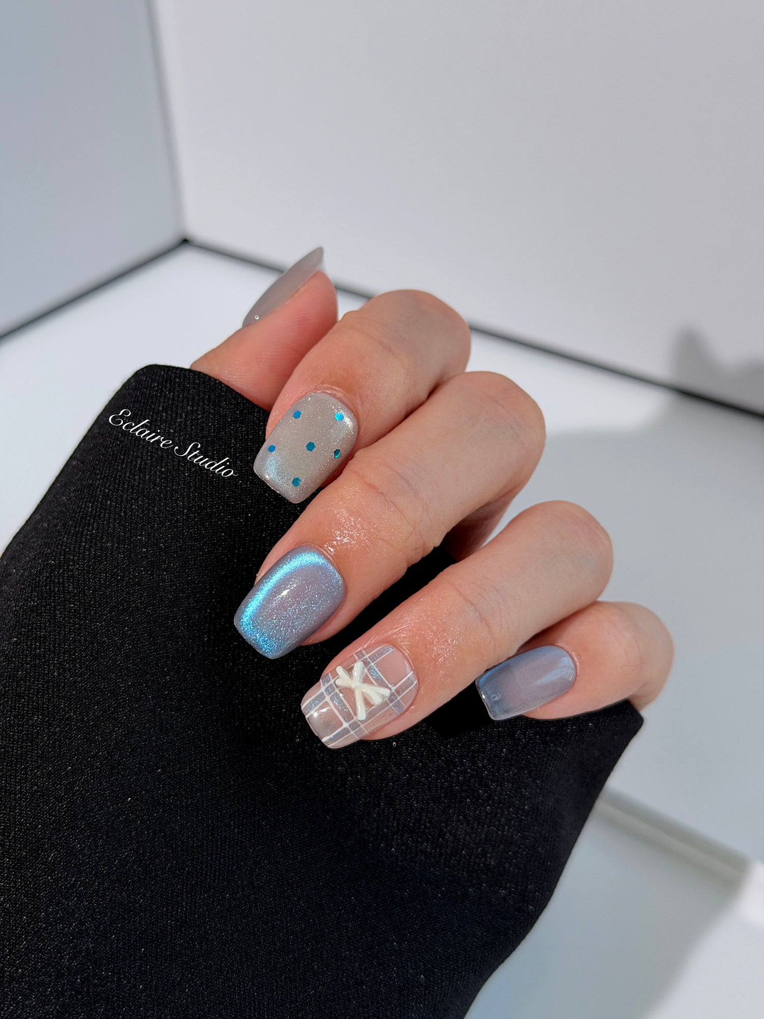 Pastel blue cat-eye press-on nails with glitter accents and 3D clear star details in a soft winter sorbet aesthetic.
