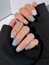 Pastel blue cat-eye press-on nails with glitter accents and 3D clear star details in a soft winter sorbet aesthetic.
