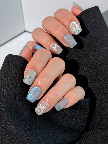 Pastel blue cat-eye press-on nails with glitter accents and 3D clear star details in a soft winter sorbet aesthetic.
