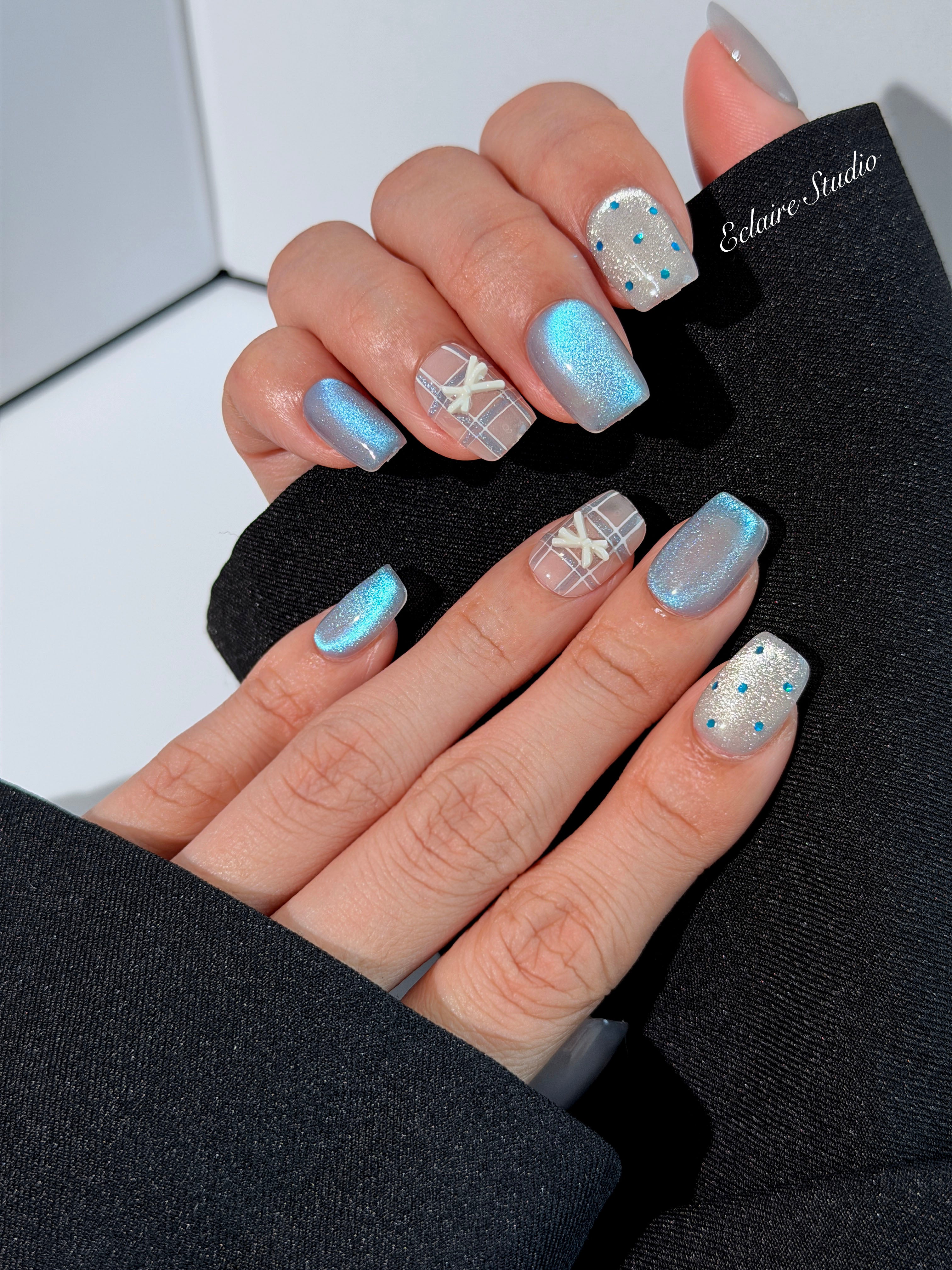 Pastel blue cat-eye press-on nails with glitter accents and 3D clear star details in a soft winter sorbet aesthetic.
