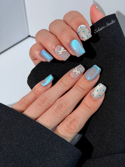 Pastel blue cat-eye press-on nails with glitter accents and 3D clear star details in a soft winter sorbet aesthetic.
