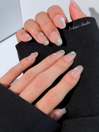Short milky nude press-on nails with iridescent glitter and 3D crystal droplets, soft winter sugar aesthetic.
